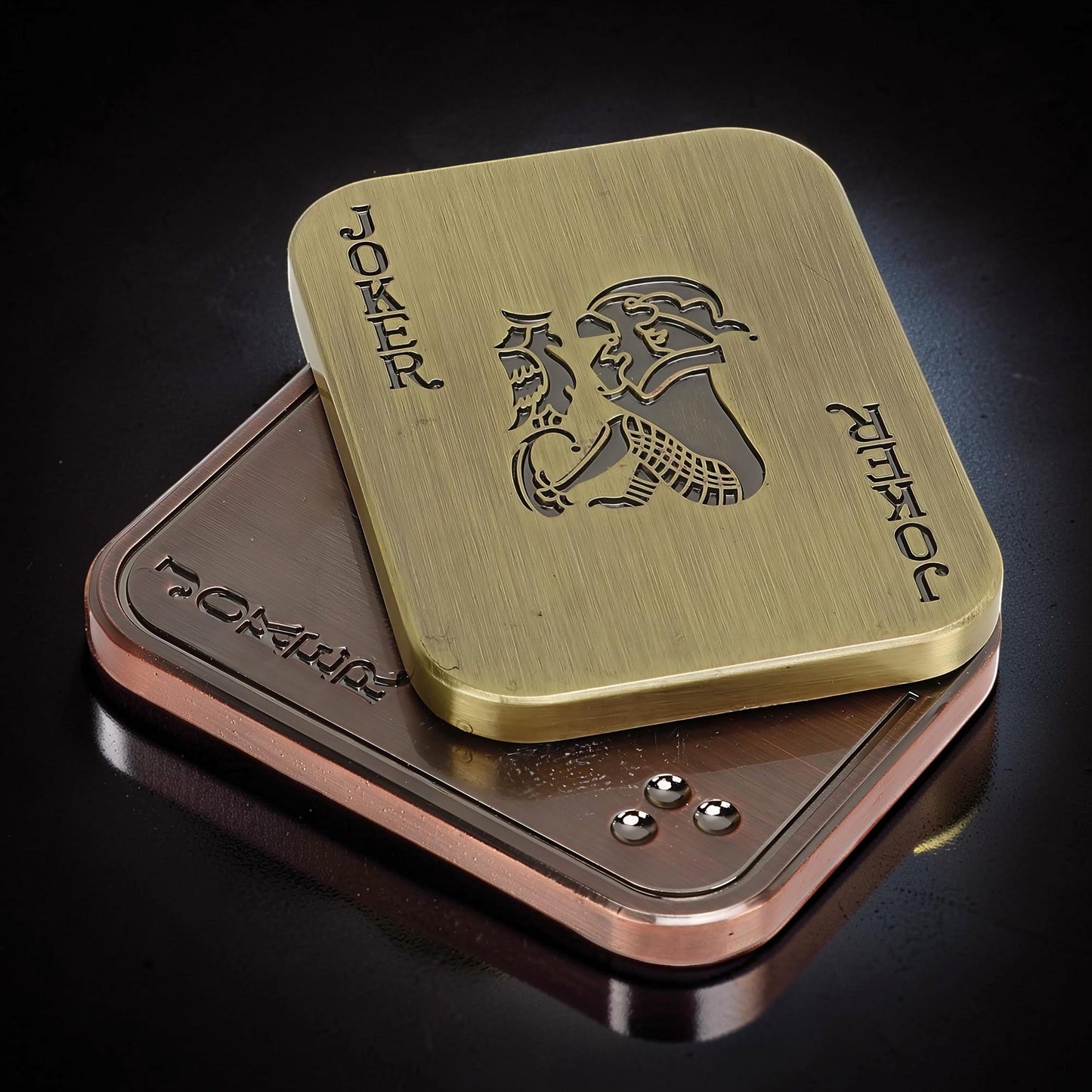 The Curious Mind Joker Poker Magnetic Slider fidget toy in brass and copper finishes, shaped like a playing card.