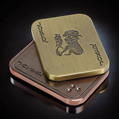 The Curious Mind Joker Poker Magnetic Slider fidget toy in brass and copper finishes, shaped like a playing card.