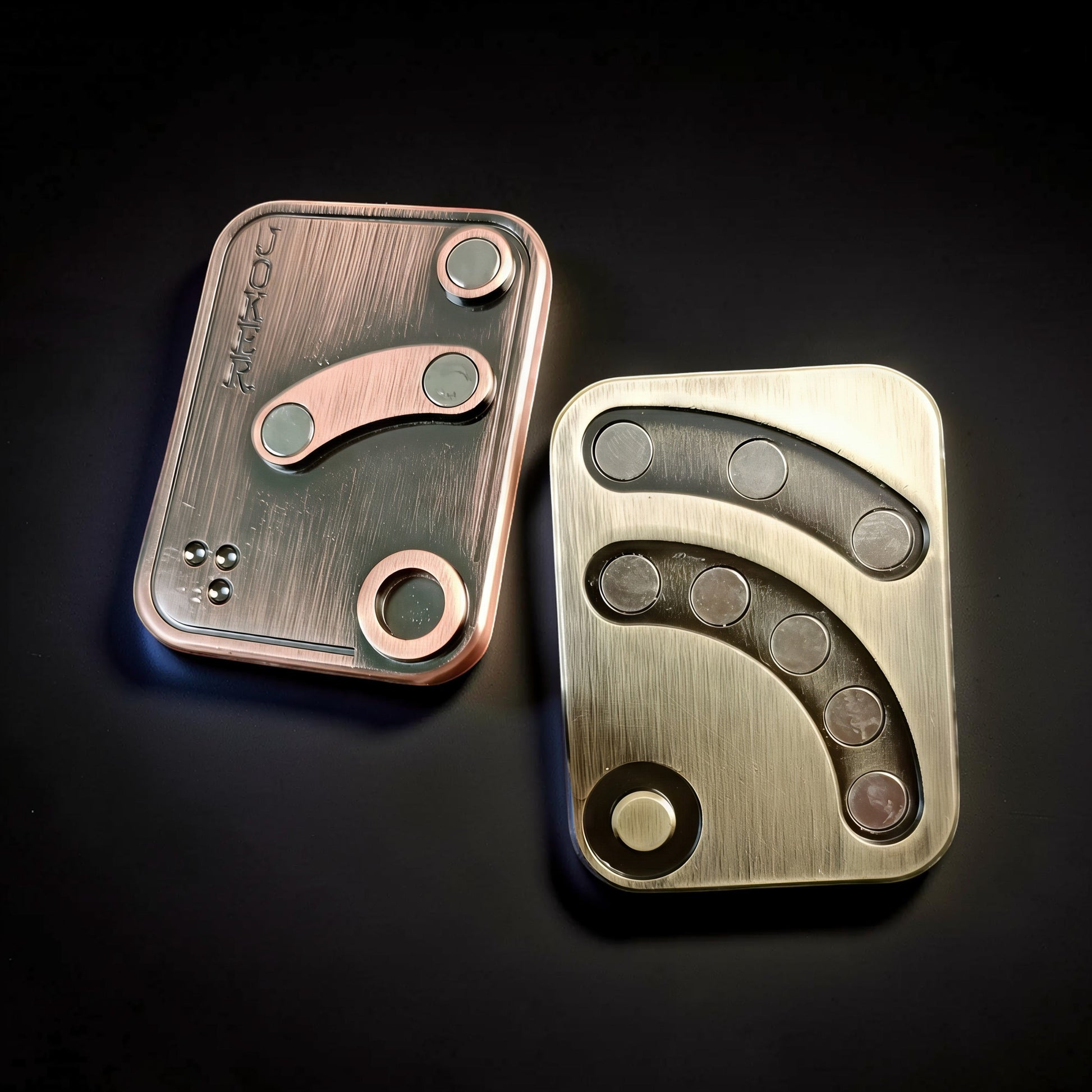 The Curious Mind Joker Poker magnetic slider fidget toy in antique bronze and brass finishes. Metal construction with tactile magnetic push-and-return action.