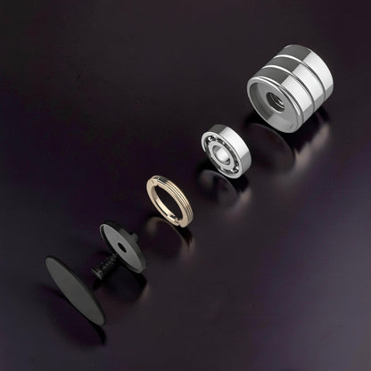 The Curious Mind Vortecon kinetic desk spinner disassembled: metal casing, bearing, gold ring, black base, and black cap.