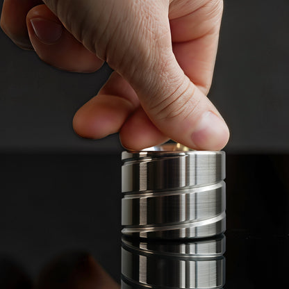 The Curious Mind Vortecon Kinetic Desk Spinner, a premium metal desk toy with a brushed silver finish and spiral design, being spun by a hand.
