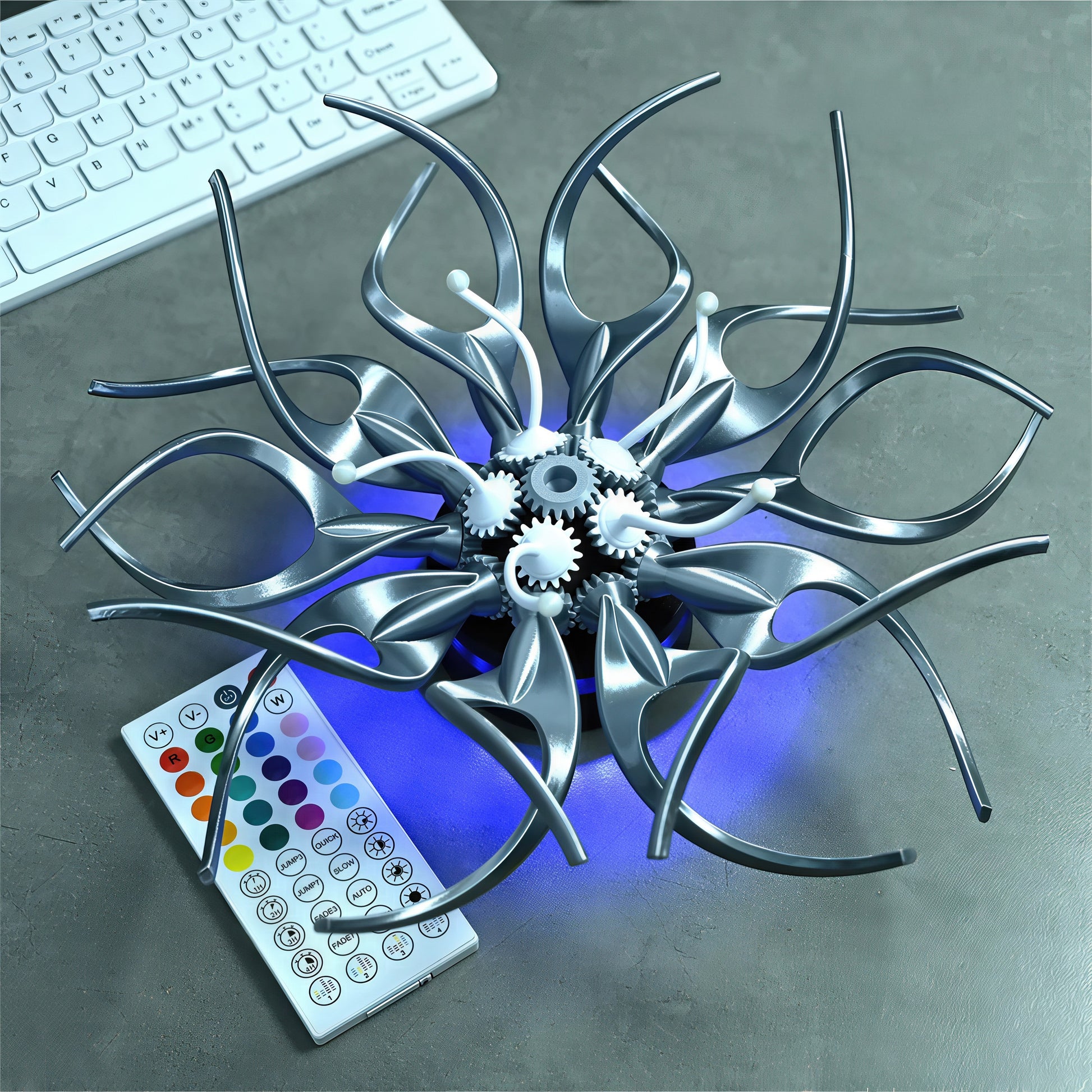 The Curious Mind Gallery Edition mechanical kinetic flower sculpture in silver PLA with visible gears and blue LED lighting. Includes remote.