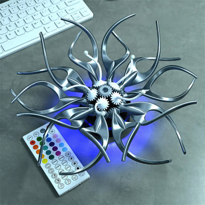 The Curious Mind Gallery Edition mechanical kinetic flower sculpture in silver PLA with visible gears and blue LED lighting. Includes remote.