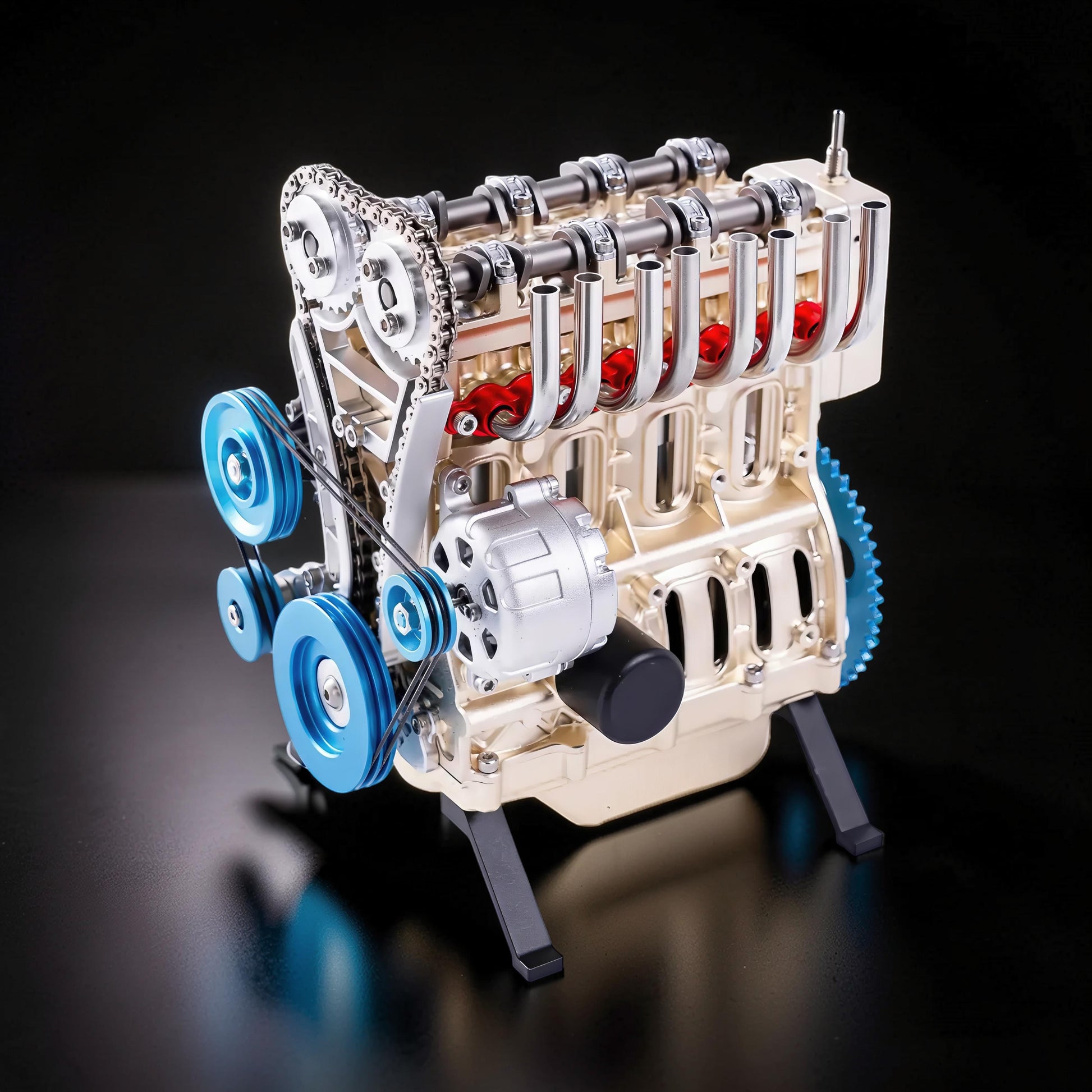 The Curious Mind L4 four-cylinder engine model kit, gold metal construction with blue pulleys and red accents.