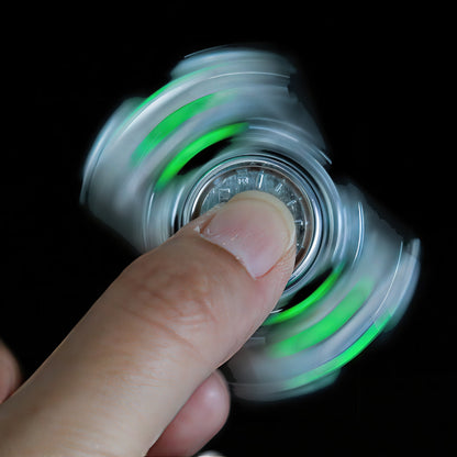 The Curious Mind Luminous Tank Metal Spinner with green glowing accents, held by a finger and spinning.
