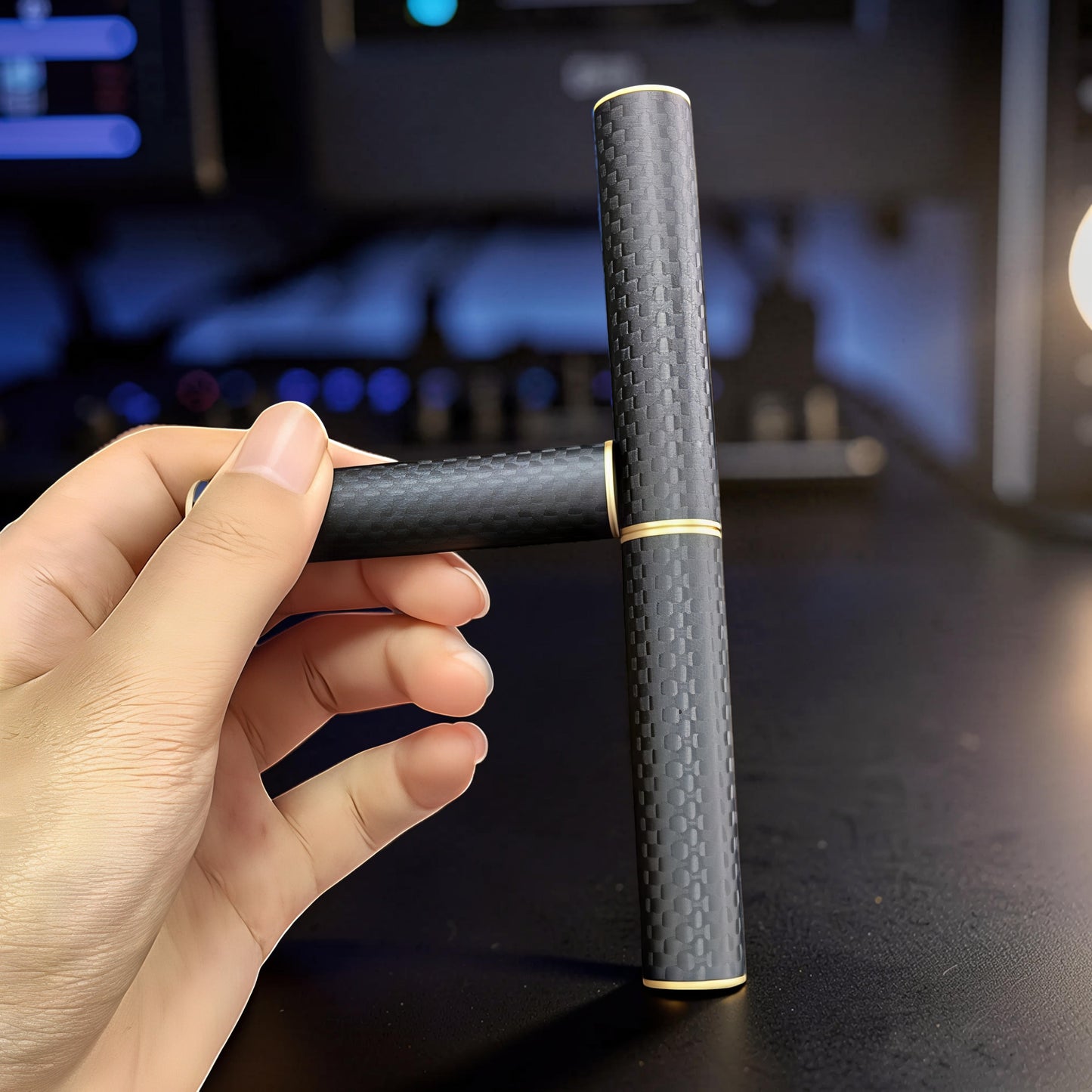 The Curious Mind Magnetic Carbon Fiber Slider fidget toy with gold accents. A hand holds the slider in a T-shape.