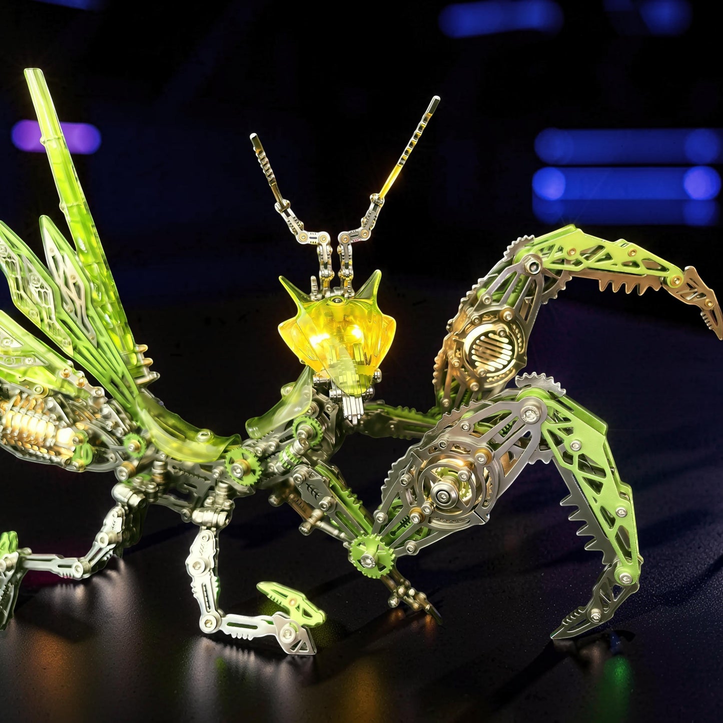The Curious Mind Mechanical Mantis 3D metal model kit with green and silver metallic parts and a glowing yellow head.