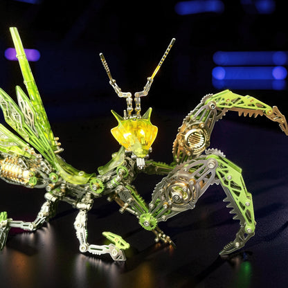 The Curious Mind Mechanical Mantis 3D metal model kit with green and silver metallic parts and a glowing yellow head.