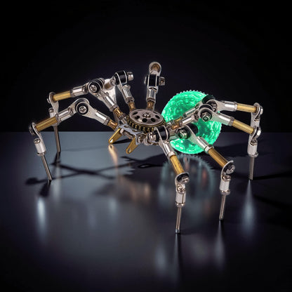 The Curious Mind Style G mechanical spider DIY kit, made of metal with a glowing green orb abdomen.