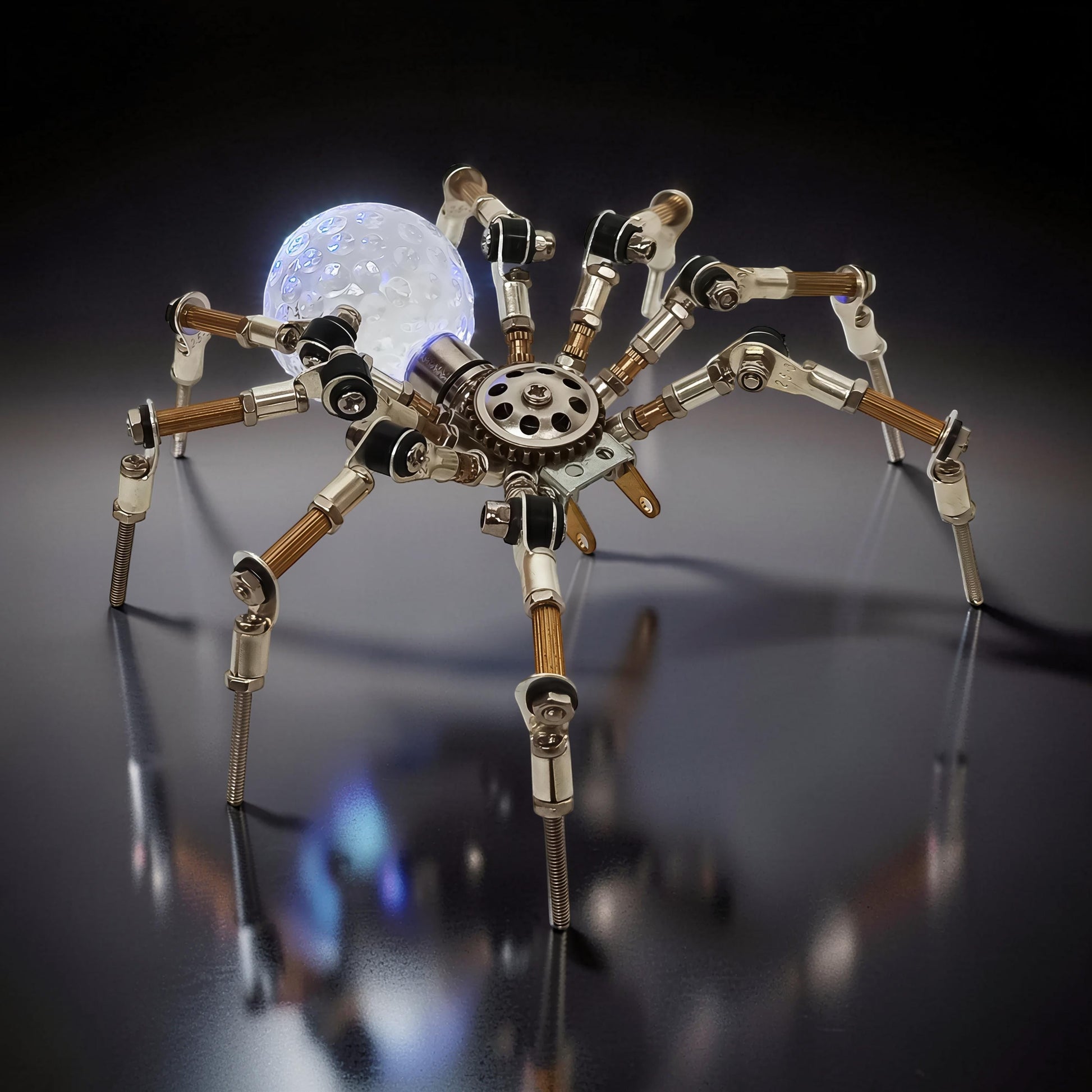 The Curious Mind Style G mechanical spider DIY kit, made of metal with a glowing orb.