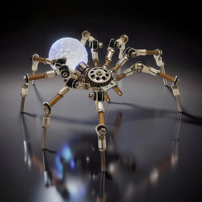 The Curious Mind Style G mechanical spider DIY kit, made of metal with a glowing orb.