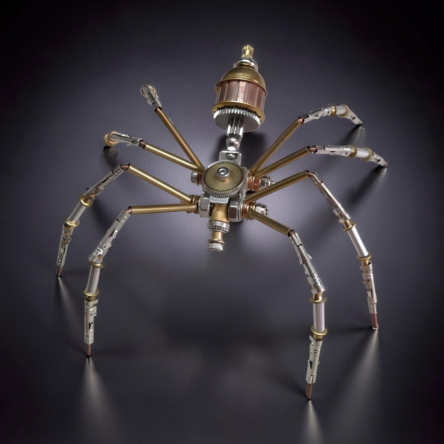 The Curious Mind Style C mechanical spider model kit, made of metal with brass and silver accents, featuring intricate gears and articulated legs.