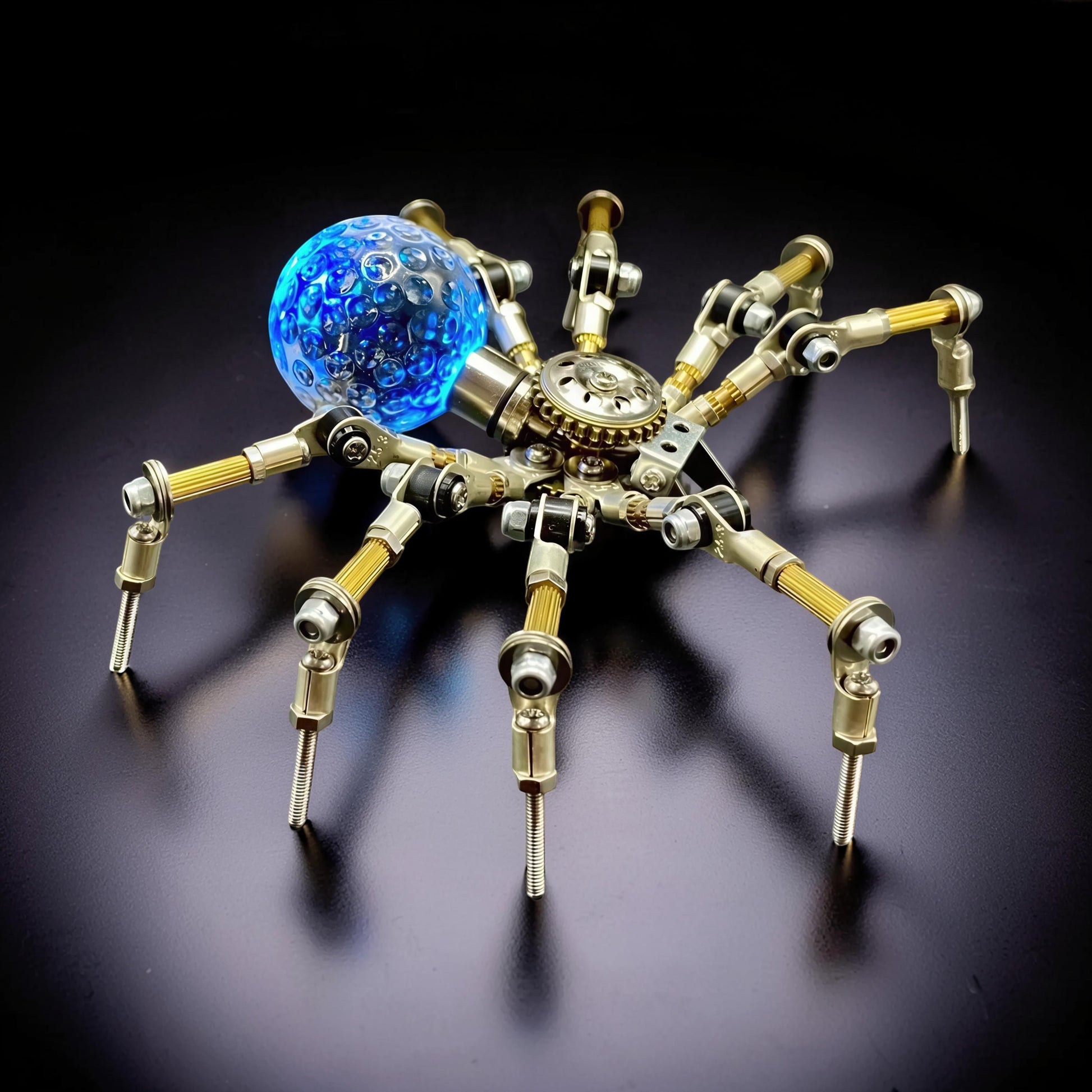 The Curious Mind Style G mechanical spider model kit, made of metal with a blue glass orb.