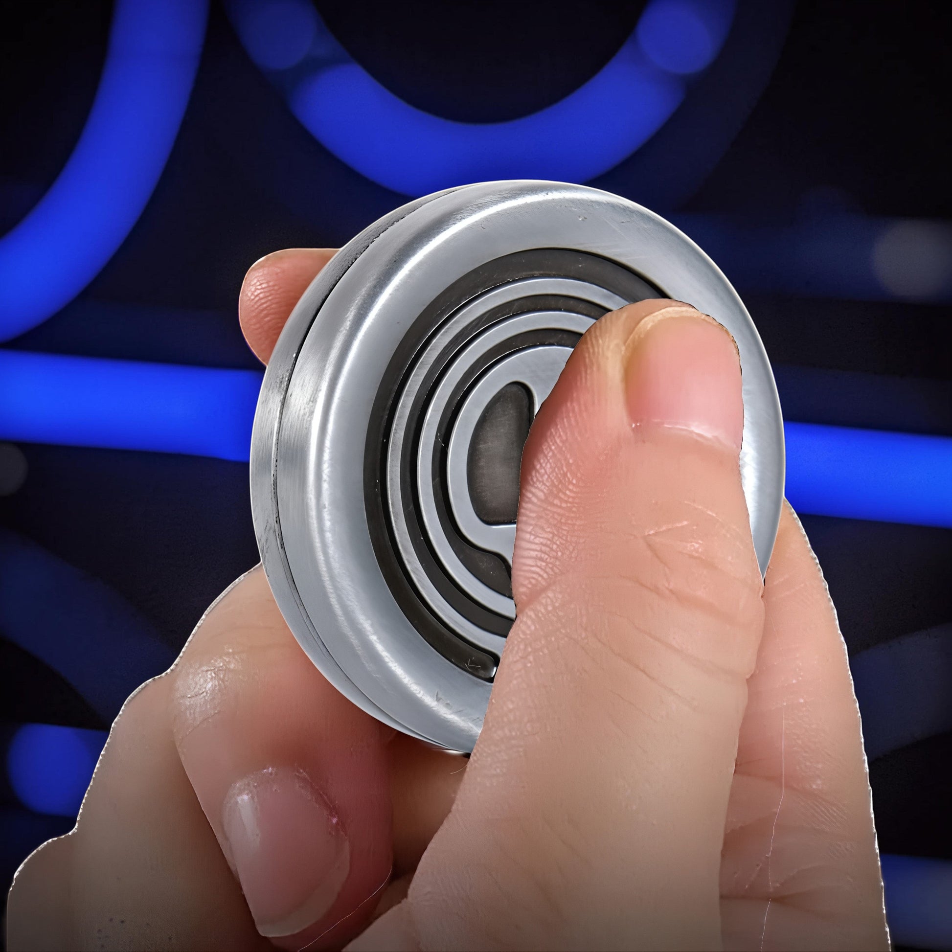 The Curious Mind Demon Coin Push Card Clicker, a compact metal fidget toy with a silver finish and black concentric circle design, held in a hand.