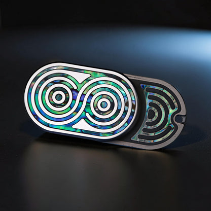 The Curious Mind Fritillary Push Slider fidget toy with iridescent abalone inlay and silver accents.