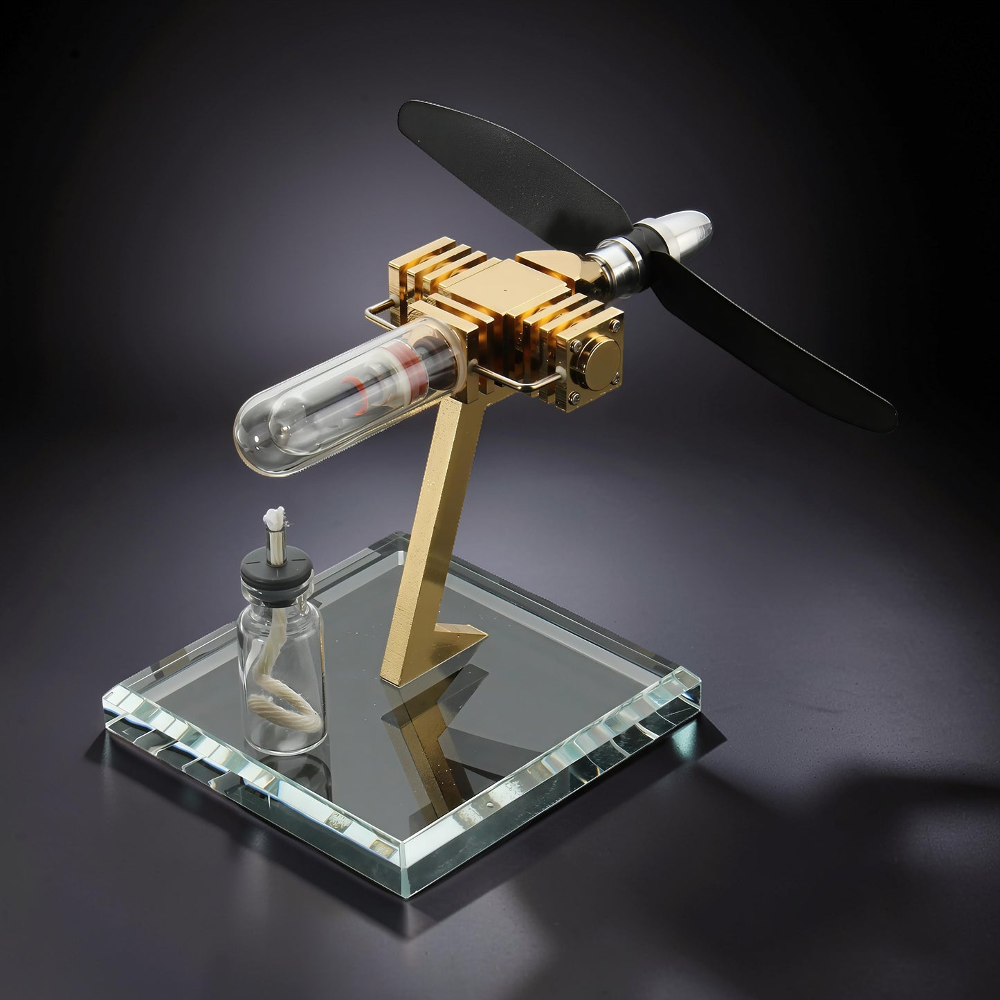 The Curious Mind Mini Aircraft Stirling Engine display model, made of metal with a glass cylinder and black propeller.