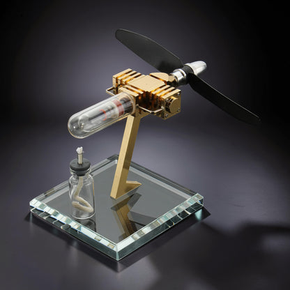 The Curious Mind Mini Aircraft Stirling Engine display model, made of metal with a glass cylinder and black propeller.