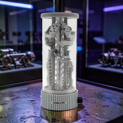 The Curious Mind Spinning Pinball RGB Night Light features a grey PLA construction with a clear cylinder, showcasing intricate tracks and balls. It has a ribbed base with a dial and emits ambient light.
