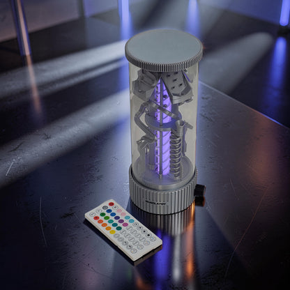 The Curious Mind Spinning Pinball RGB Night Light features a clear cylinder with internal mechanical elements and purple LED lighting, includes a remote control.
