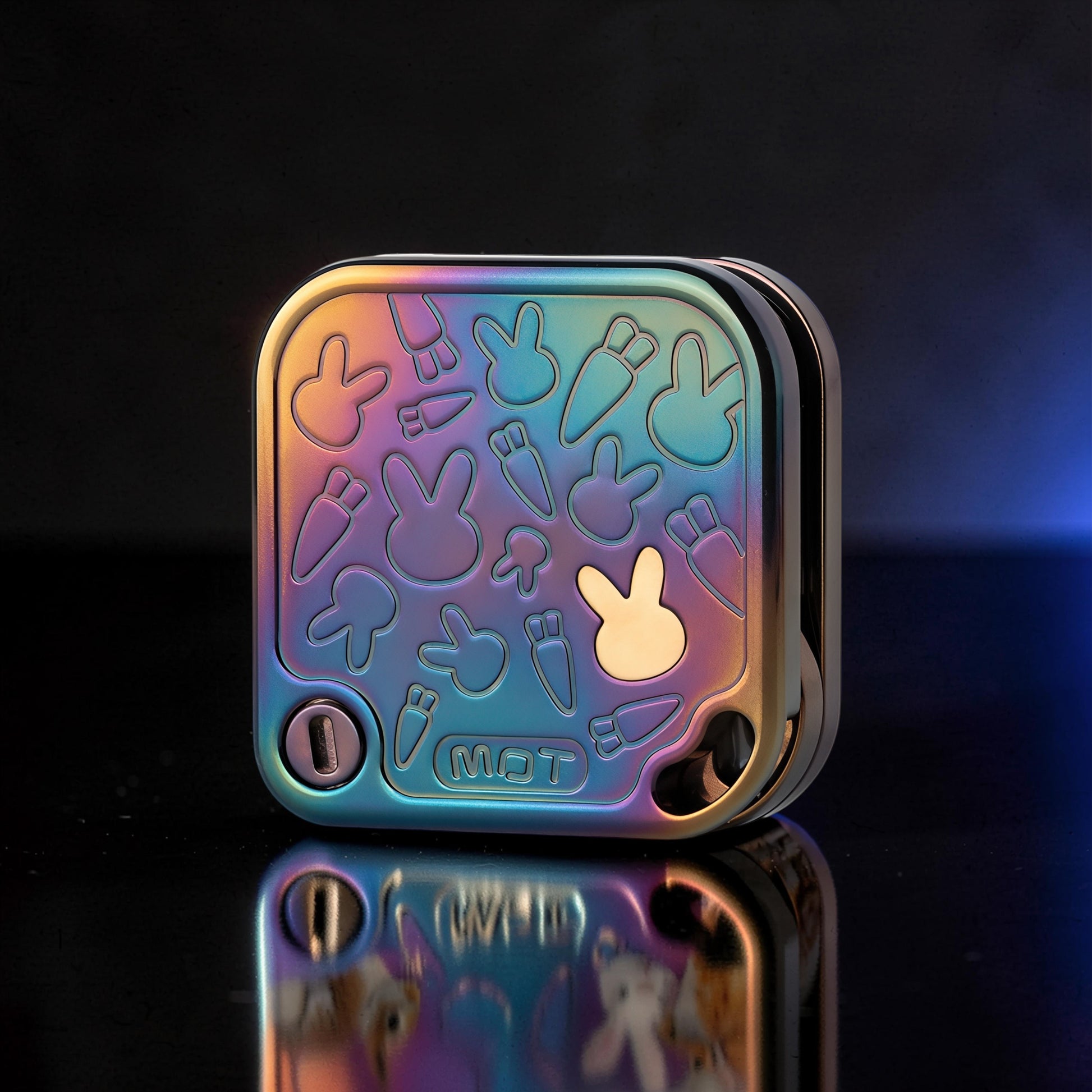 The Curious Mind Rabbit Tuning Fork Clicker fidget toy with a rainbow iridescent metal finish and embossed bunny and carrot designs.