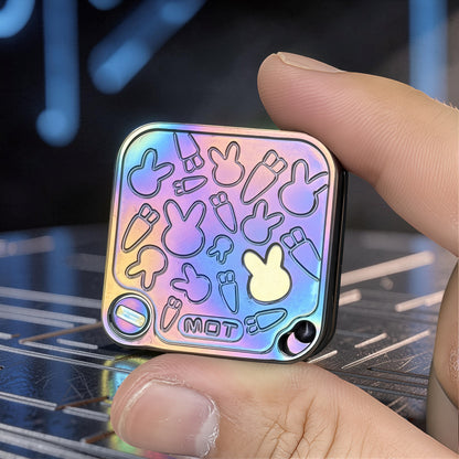 The Curious Mind Rabbit Tuning Fork Clicker fidget toy with a rainbow iridescent metal finish and embossed bunny and carrot designs.