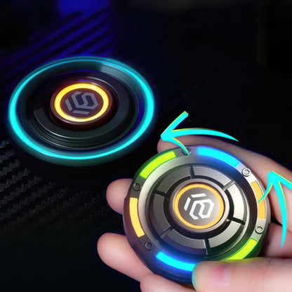 The Curious Mind Nebula RGB Disc Spinner, a metallic, round fidget toy with illuminated blue and yellow accents, held in a hand.