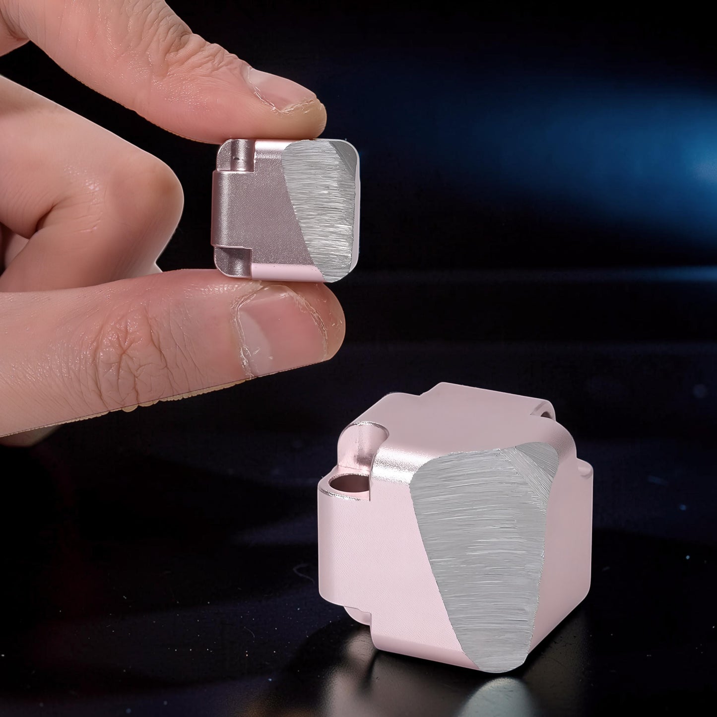 The Curious Mind Unlimited Magic Fidget Cube in rose gold metal, held between fingers. Compact, geometric desk toy.