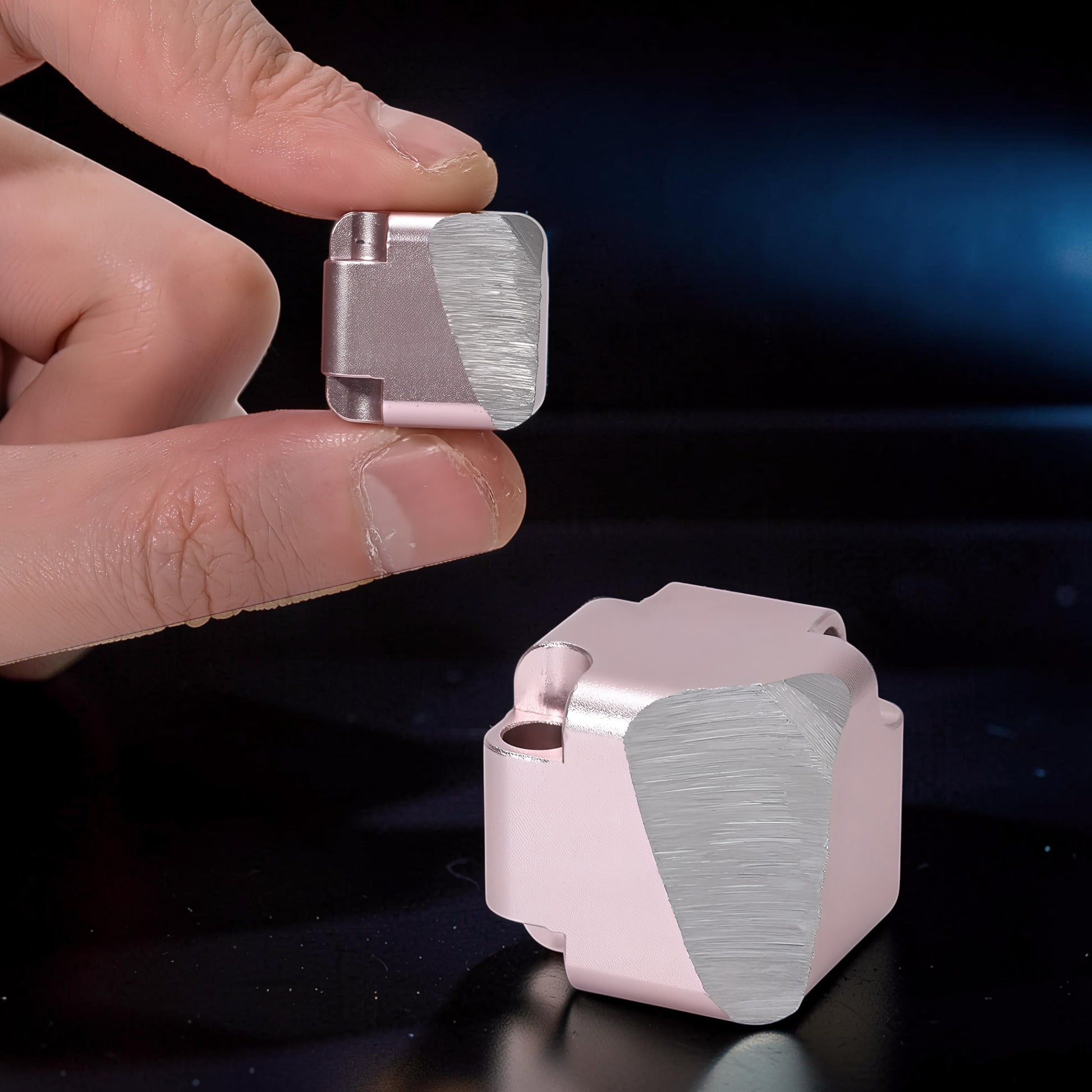 The Curious Mind Unlimited Magic Fidget Cube in rose gold metal, held between fingers. Compact, geometric desk toy.