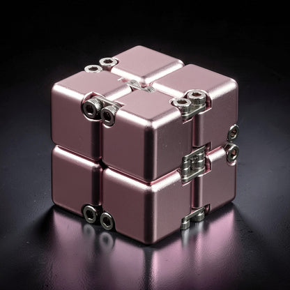The Curious Mind Unlimited Magic Fidget Cube in rose gold metal with visible screws and hinges.