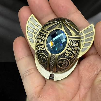 The Curious Mind Scarab Metal EDC Fidget Spinner with blue gem and winged design, held in hand.