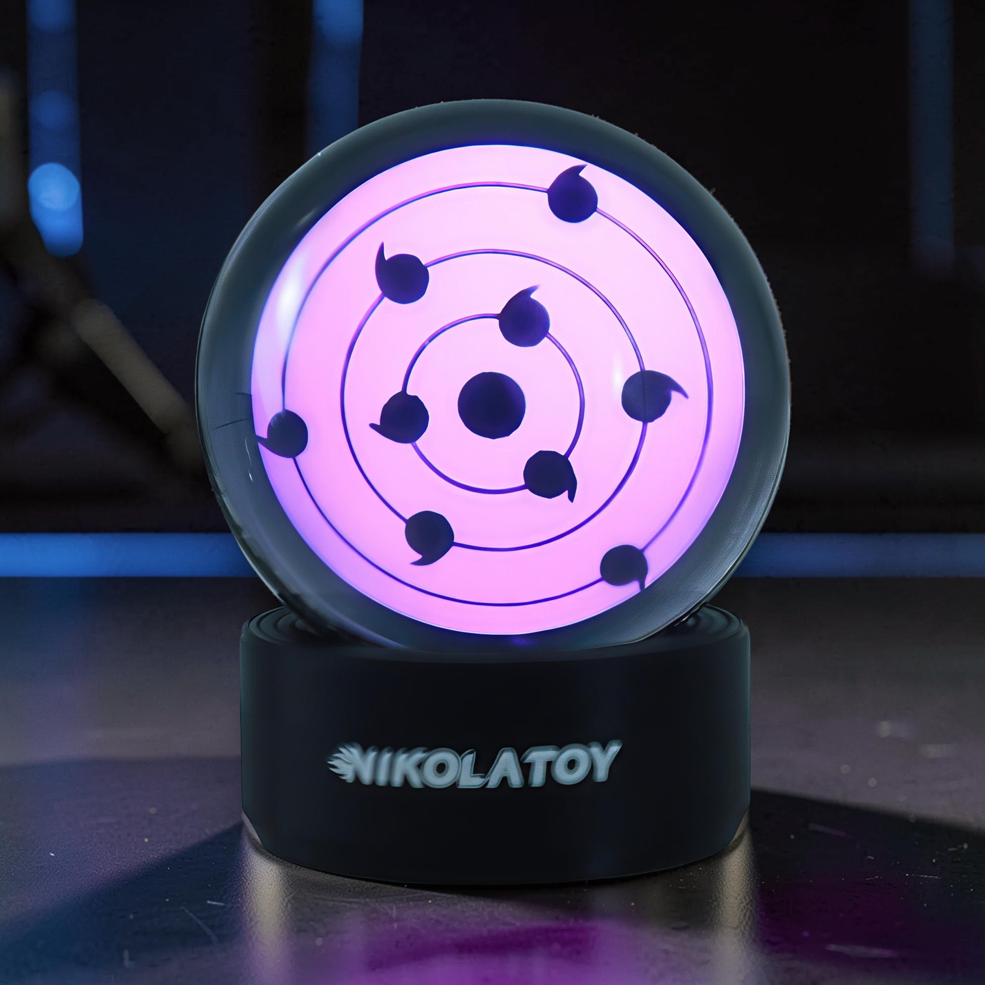 The Curious Mind Sharingan Crystal Ball Decorative Ornament, a pink glowing orb with black tomoe patterns on a black base.