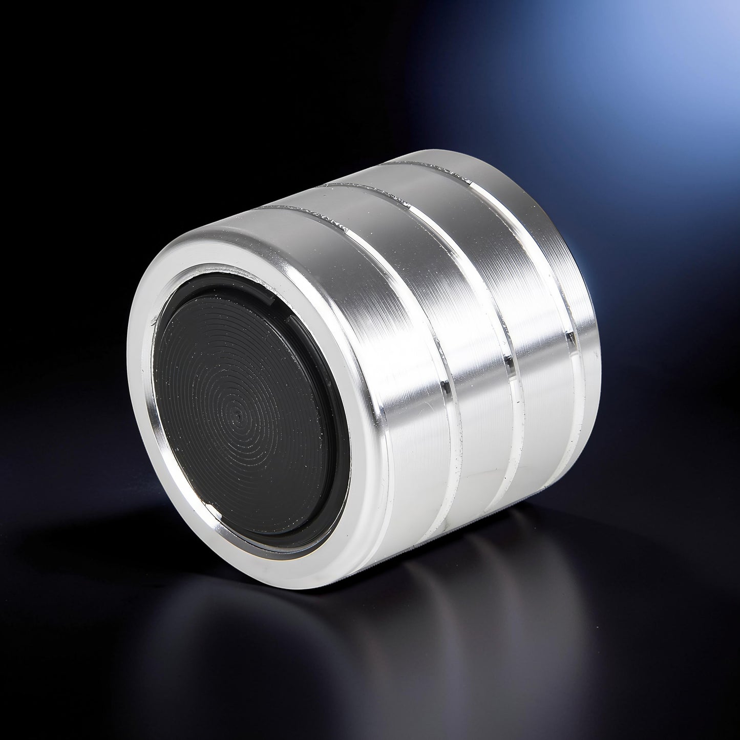 The Curious Mind Vortecon kinetic desk spinner is silver metal with a black textured grip. It has a weighted, cylindrical design with grooved detailing.