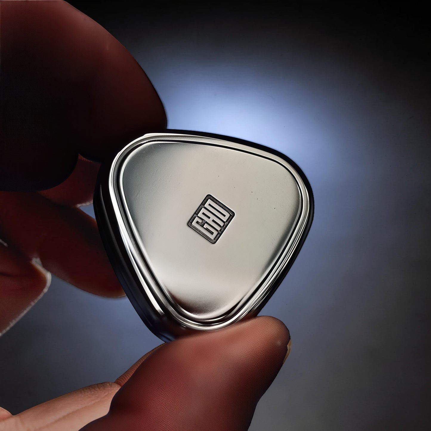 The Curious Mind's silver metal rice ball push card fidget with a logo in the center. Compact and sleek.