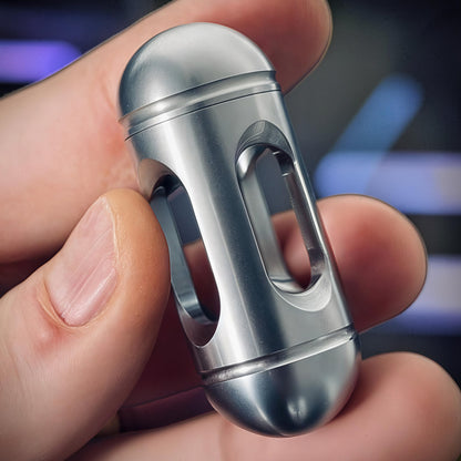 The Curious Mind silver metal egg pocket spinner fidget toy with a smooth, rounded design and open cutouts.