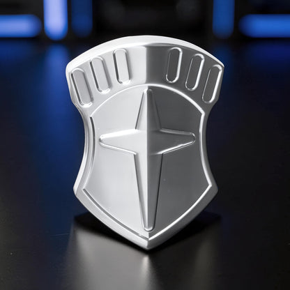 The Curious Mind Shield Fingertip Spinner, a compact silver metal fidget toy with a shield design and star emblem.
