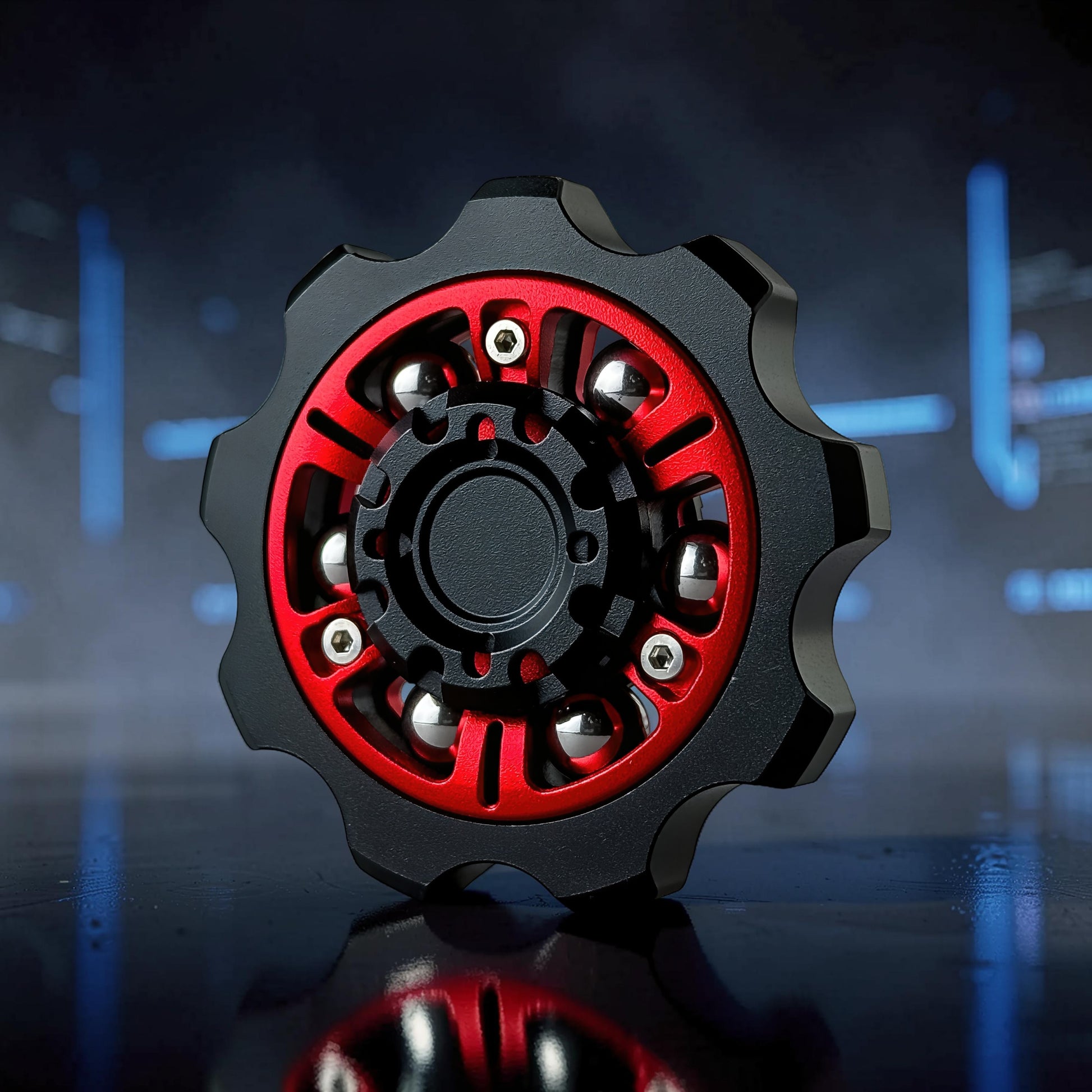 The Curious Mind Six-Bead Gear Spinner in black and red metal with silver bearings, designed like a gear for fidgeting and display.