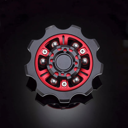 The Curious Mind Six-Bead Gear Spinner in black and red metal with six silver ball bearings. Gear-shaped design.