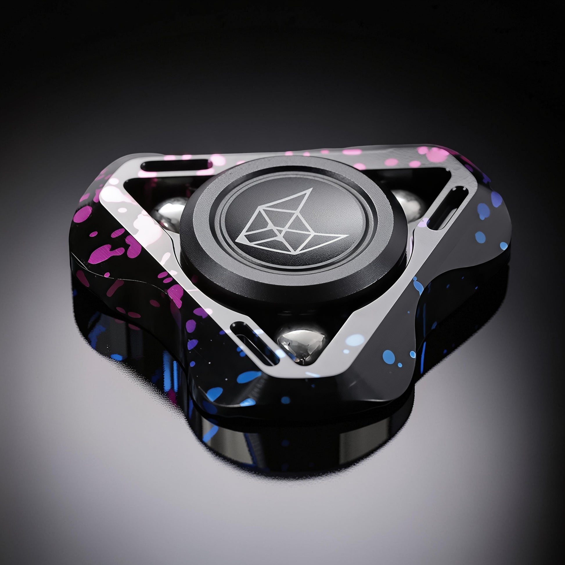 The Curious Mind Spirit Fox Glow Spinner features a black metal body with pink and blue splatter accents and a central fox logo.