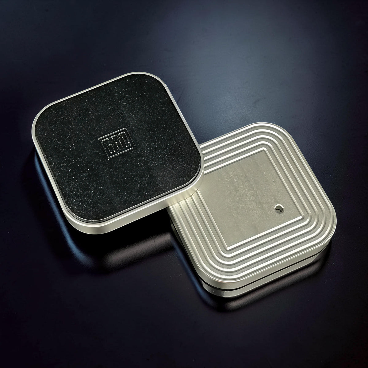 The Curious Mind Tetris Stainless Steel Slider fidget toy with a black textured top and silver ribbed base.