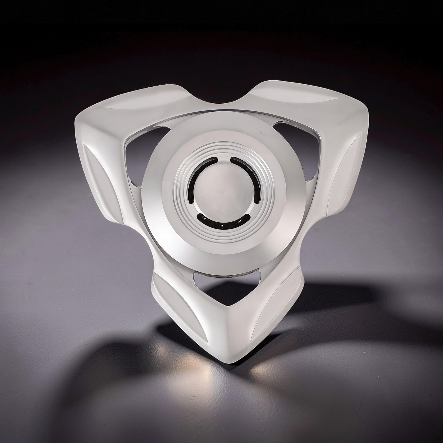 The Curious Mind stainless steel tri-blade spinner with a sleek, futuristic design and a central bearing.