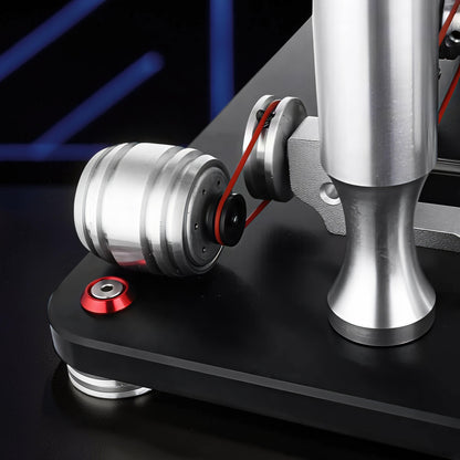 The Curious Mind Stirling Engine V4 Display Model, a metal mechanical model with a red belt and silver components on a black base.