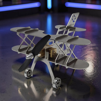 The Curious Mind Stirling Engine Model Aircraft, a silver metal biplane with a black propeller and visible mechanical engine components.