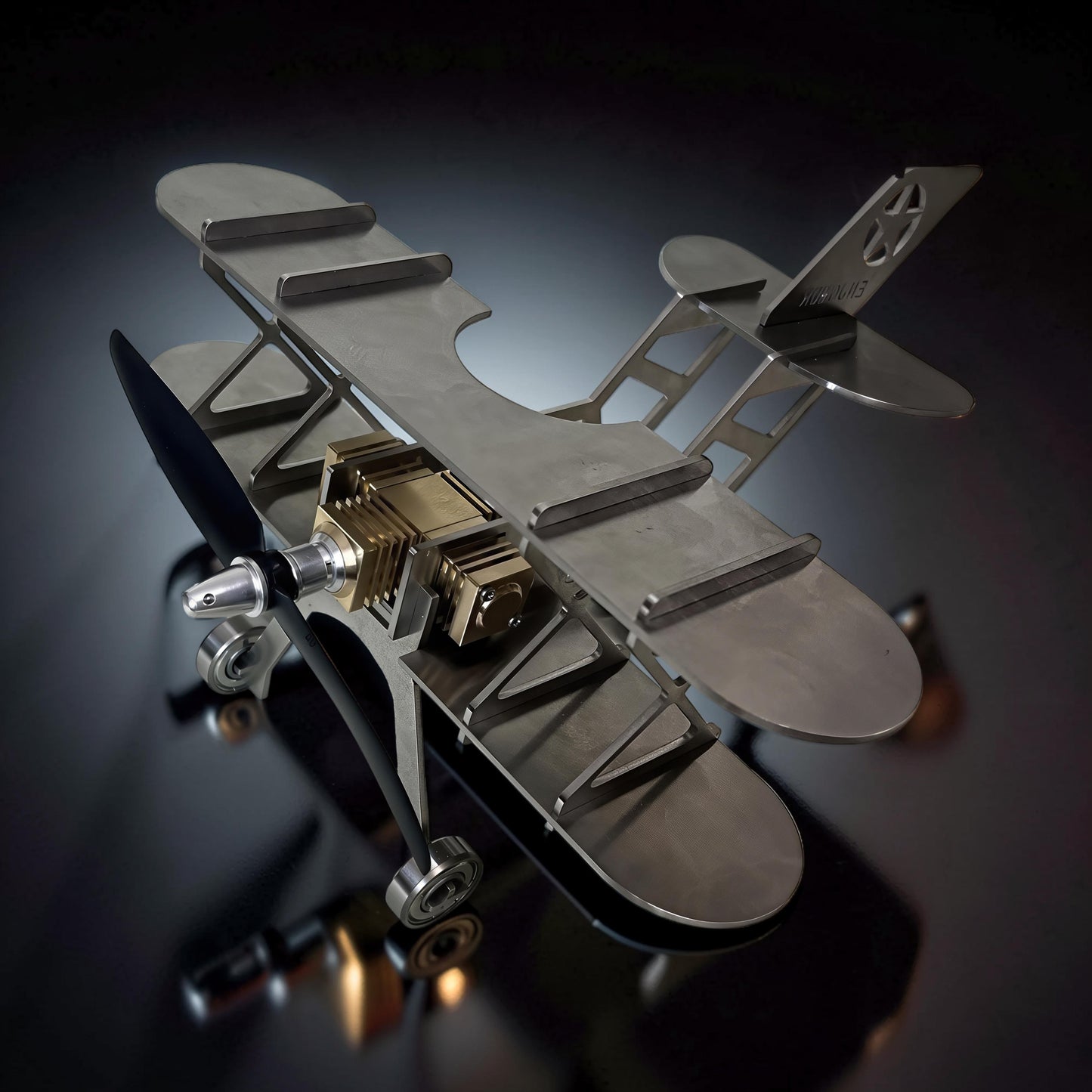 The Curious Mind Stirling Engine Model Aircraft, a metal biplane with brass engine details and a spinning propeller, ideal for desktop display.