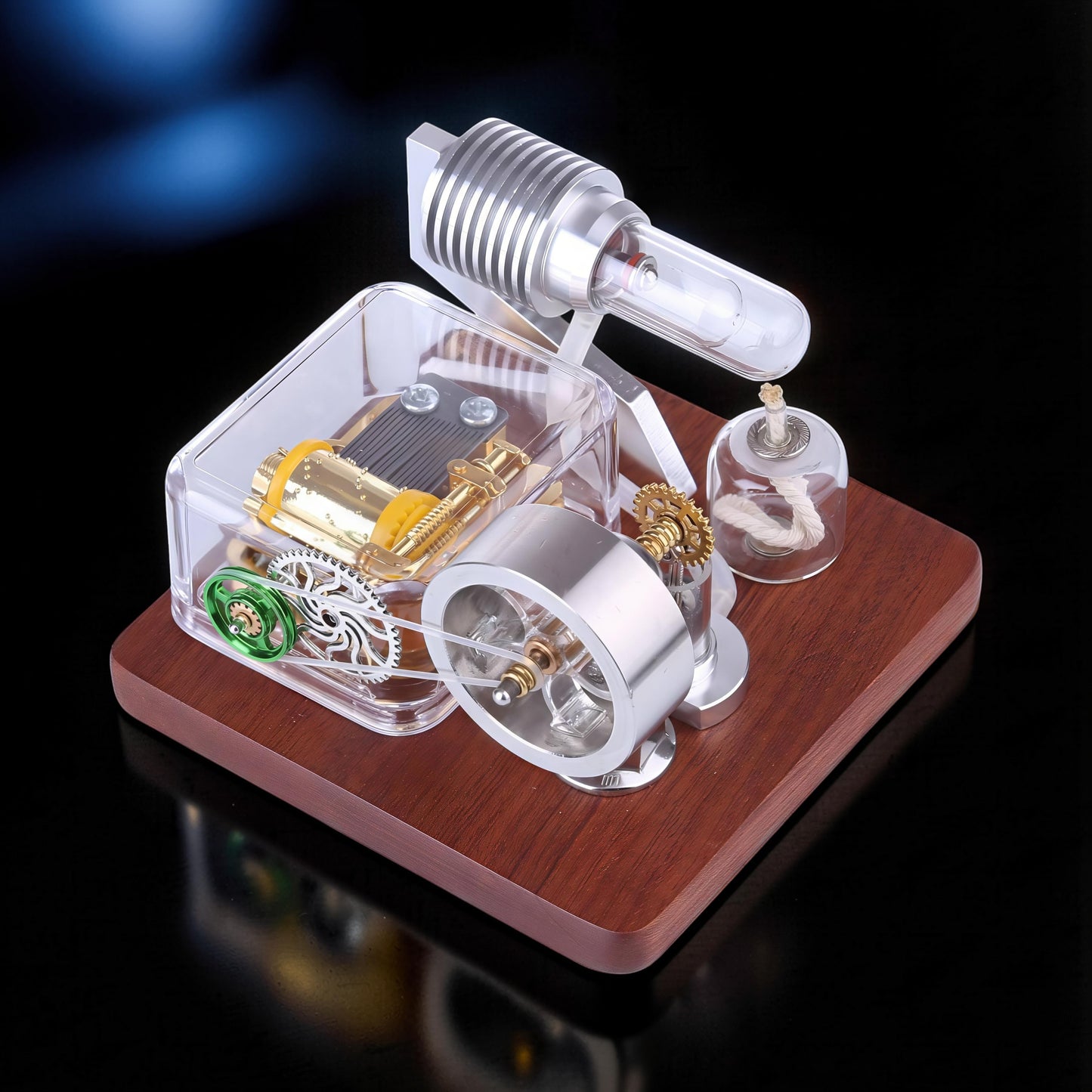 The Curious Mind Stirling Engine Music Box with metal, wood, and quartz glass construction. Features visible gears and mechanical movement.