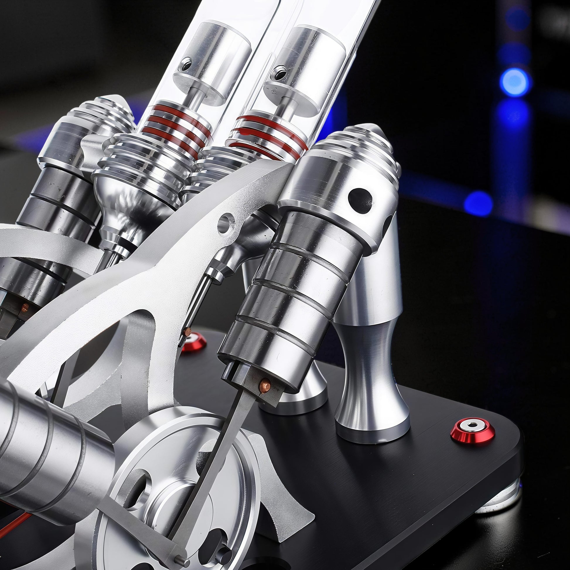 The Curious Mind Stirling Engine V4 Display Model, a metal mechanical model with clear cylinders and red accents, ideal for desks and engineering enthusiasts.