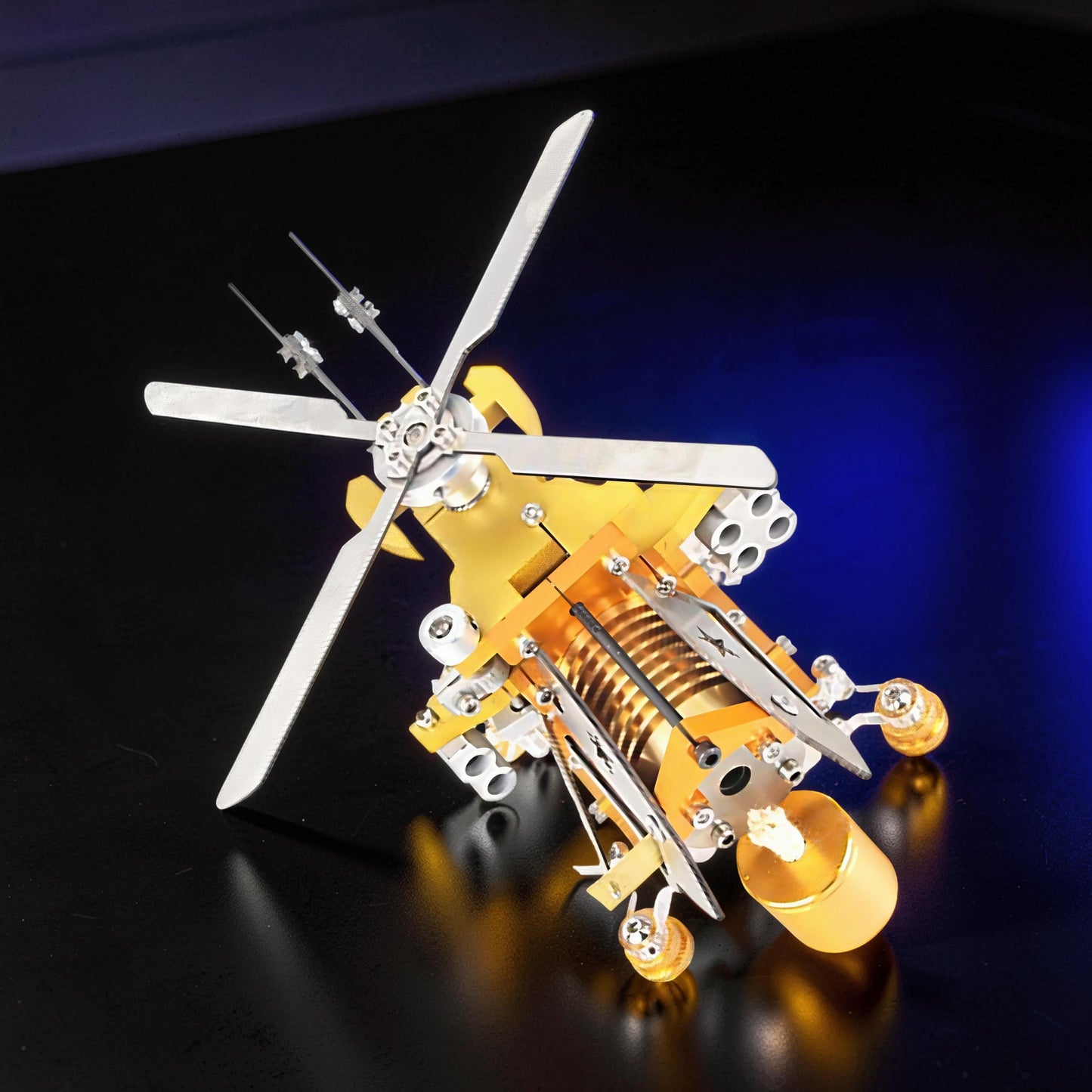 The Curious Mind Fire-Absorbing Stirling Helicopter Model, a detailed metal engine display with gold and silver accents, featuring spinning rotors and a visible Stirling engine mechanism.
