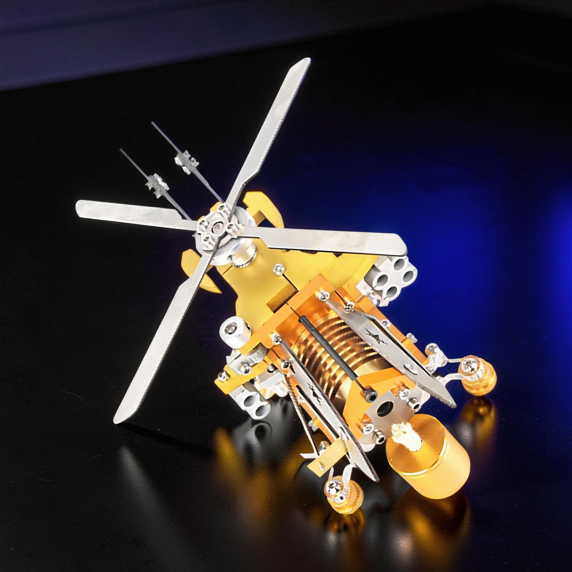 The Curious Mind Fire-Absorbing Stirling Helicopter Model, a detailed metal engine display with gold and silver accents, featuring spinning rotors and a visible Stirling engine mechanism.