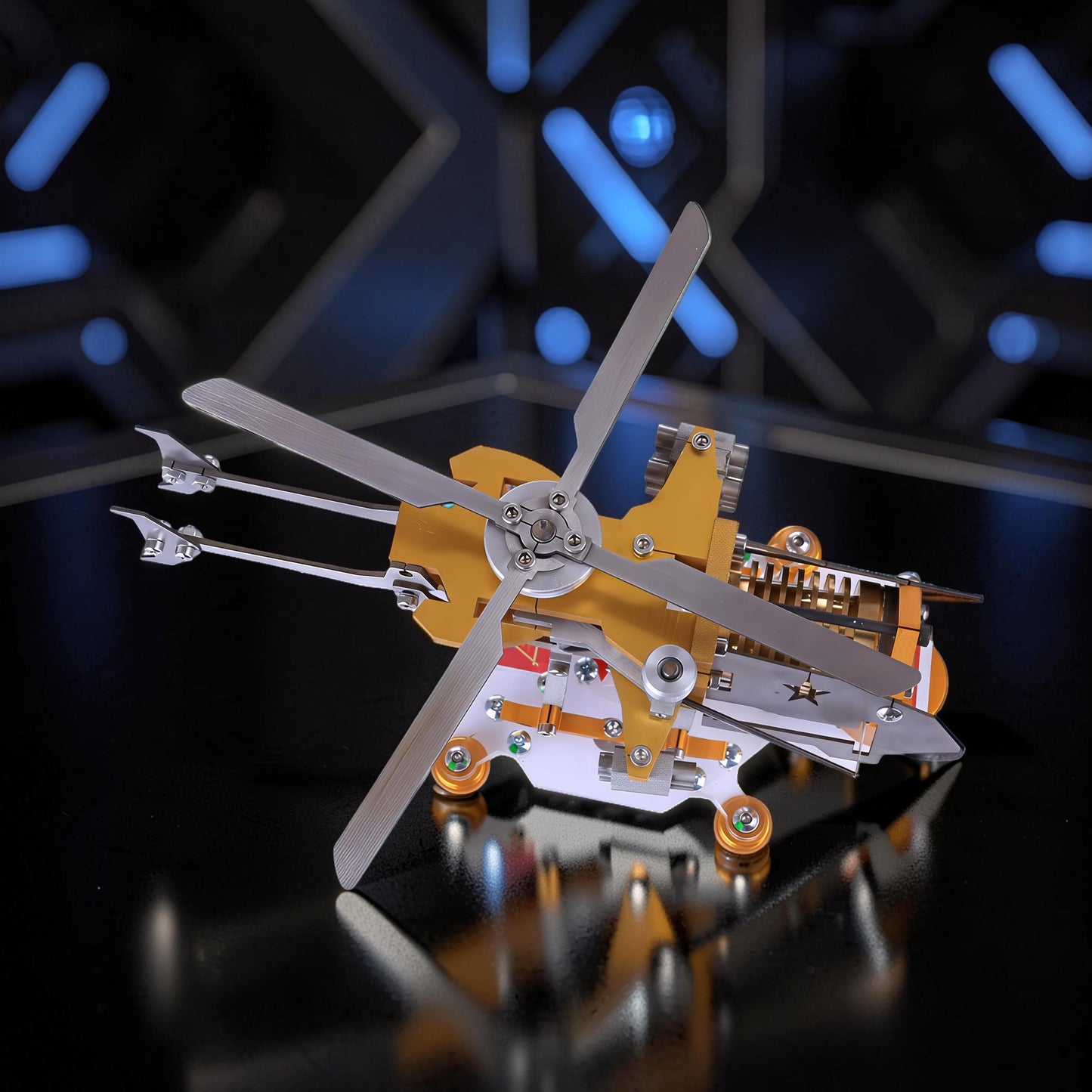 The Curious Mind Fire-Absorbing Stirling Helicopter Model is a detailed metal engine display with a gold and silver finish, featuring spinning blades and intricate mechanical parts.