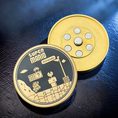 The Curious Mind Super Mario metal coin clicker fidget toy with gold and black design, featuring Mario and Nintendo branding.