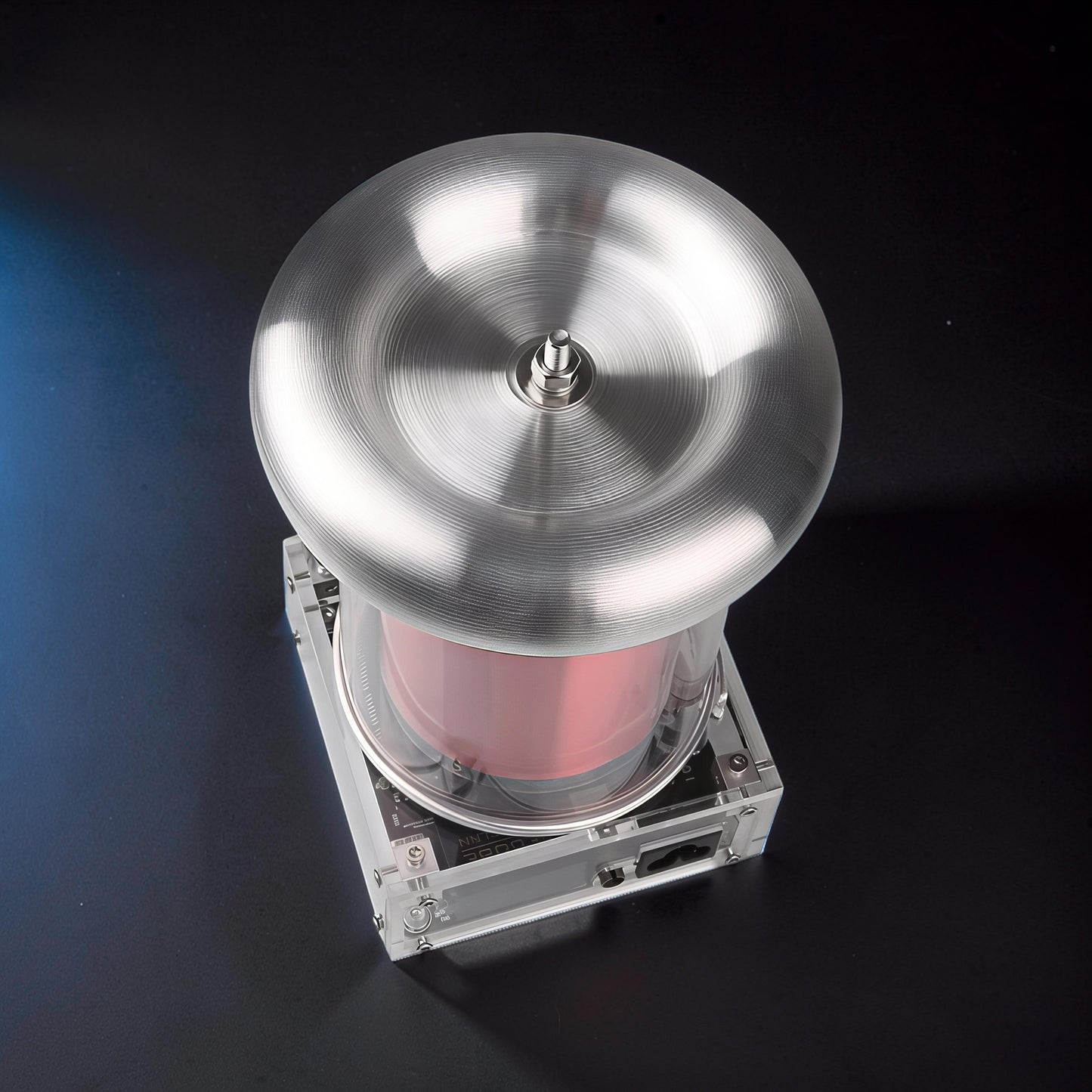 The Curious Mind Tesla Coil TC20 Plasma Science Lamp with brushed metal top and pink cylinder, on a black surface.